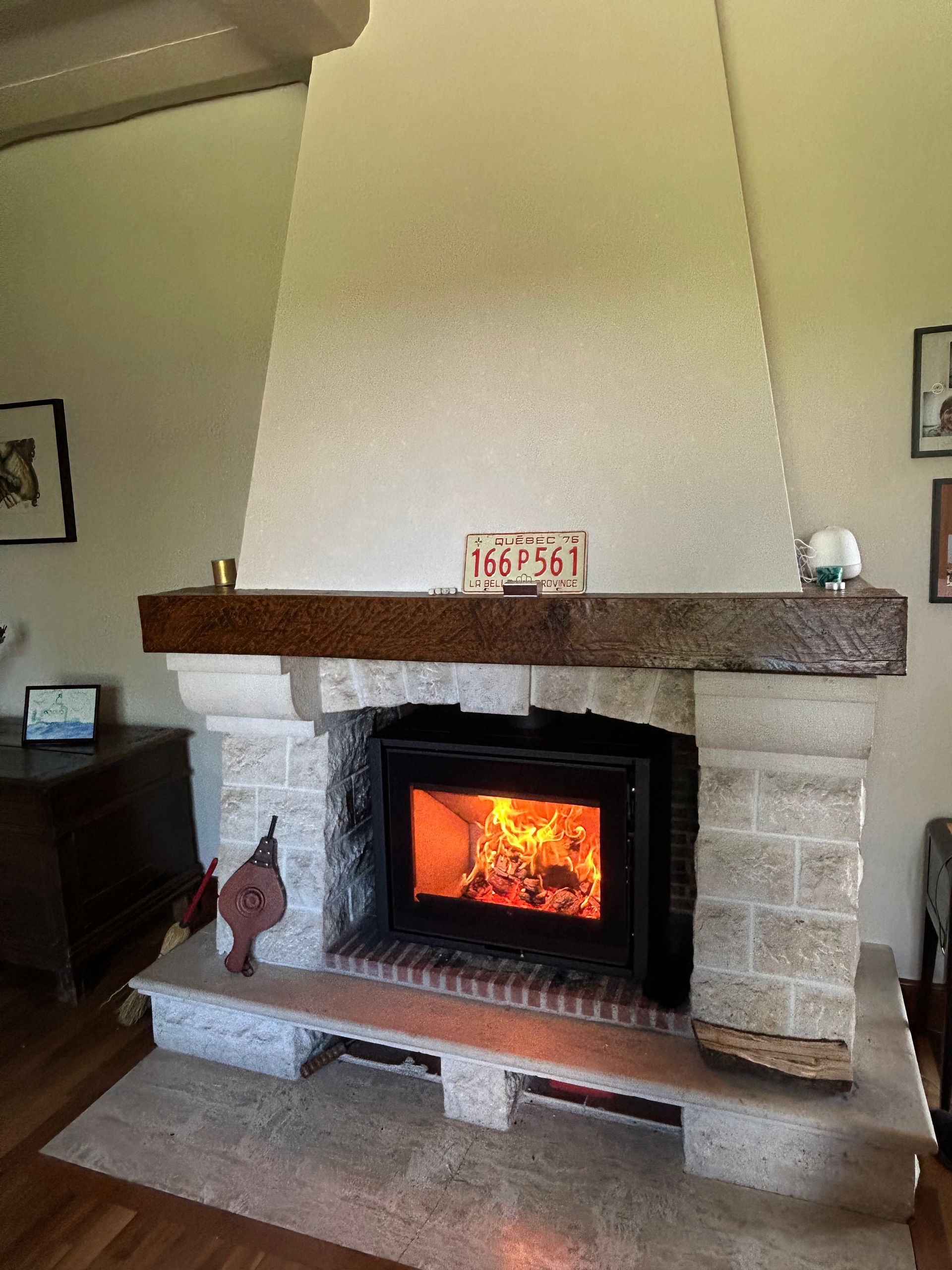 Cheminée avec feu allumé dans un encadrement en pierre et bois