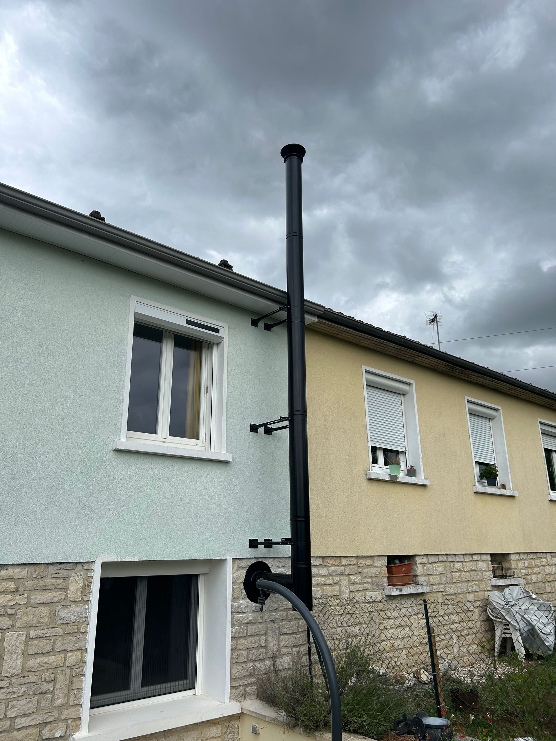 Conduit de cheminée noir fixé à l'extérieur d'un bâtiment avec des nuages sombres au-dessus