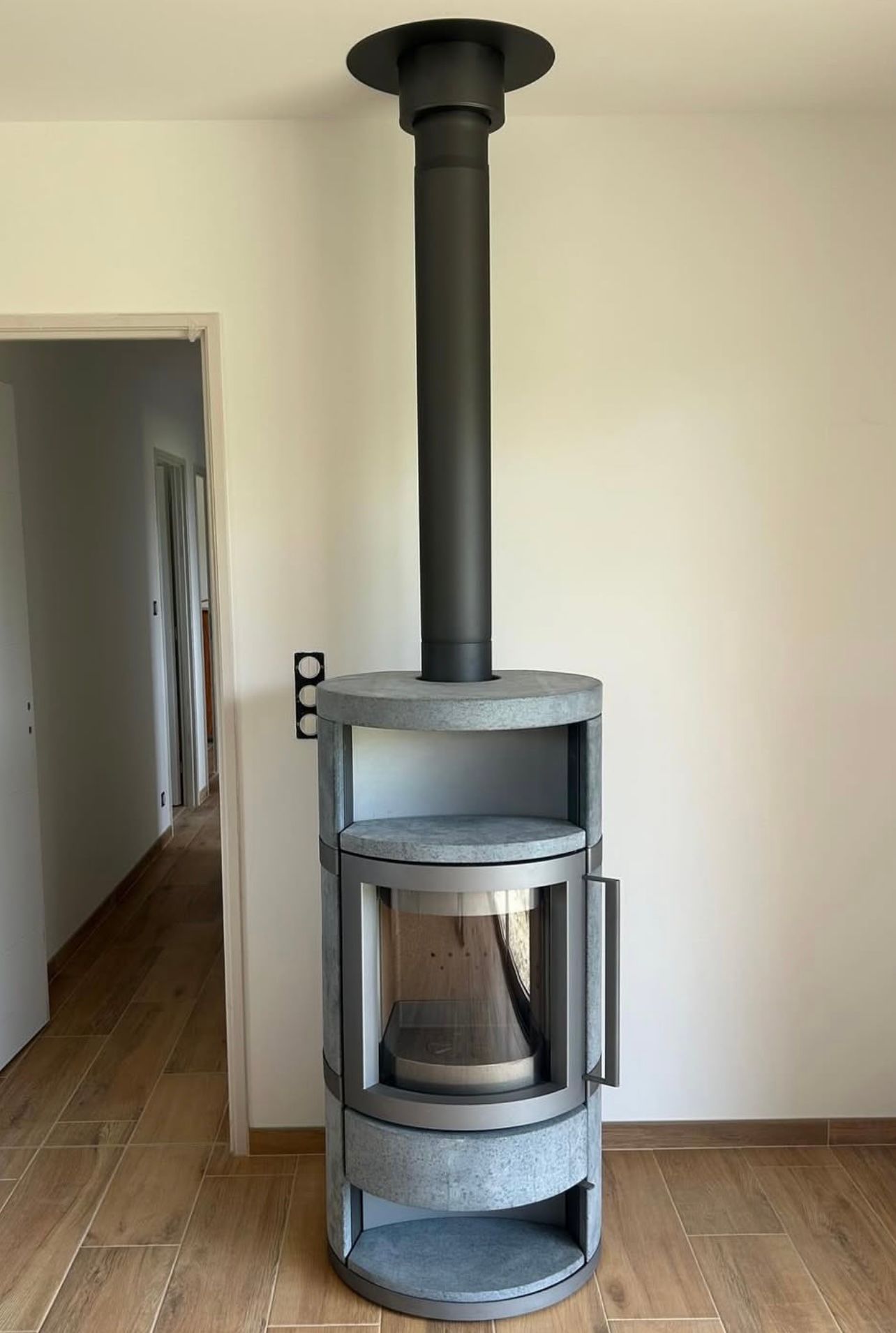 Cheminée moderne grise avec une cheminée noire dans une pièce avec parquet