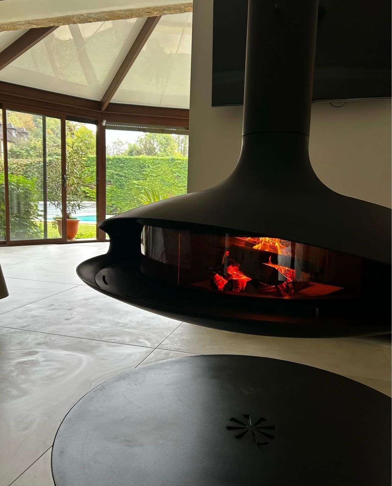 Cheminée noire moderne avec un feu flamboyant. Fenêtre vitrée avec vue sur l'extérieur