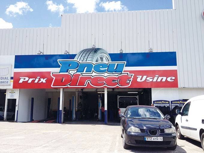 Façade du magasin Pneu Direct Usine avec un logo de pneu, une enseigne bleue et rouge.