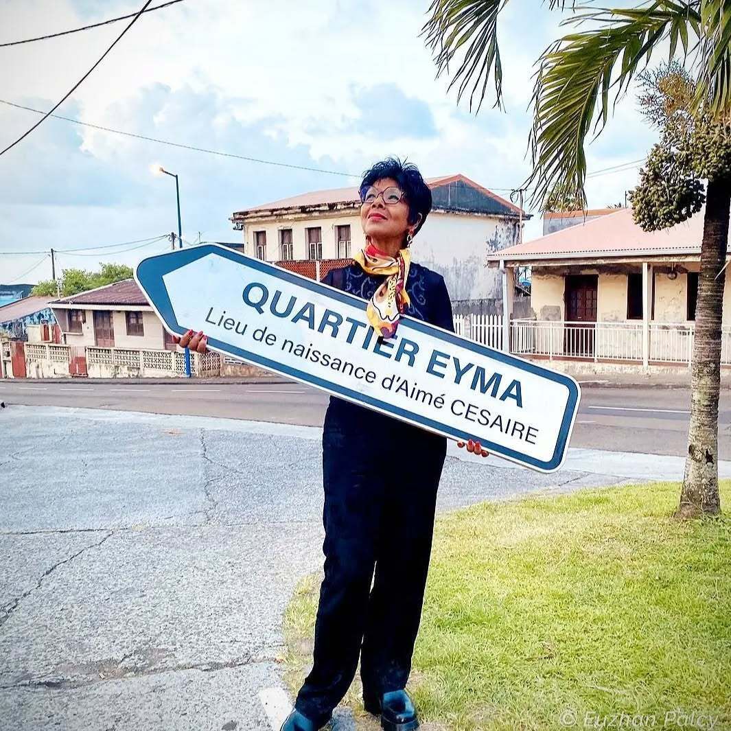 Une personne tenant une pancarte indiquant le quartier Eyma.