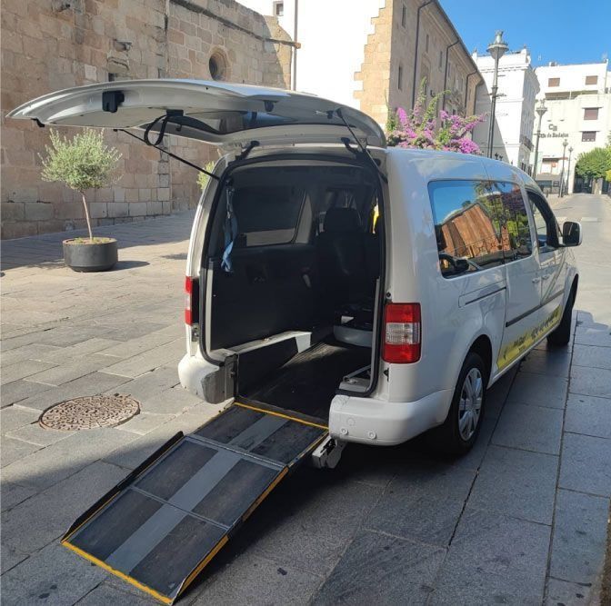 Furgoneta blanca con rampa extendida en una calle de la ciudad, diseñada para acceso de sillas de ruedas.