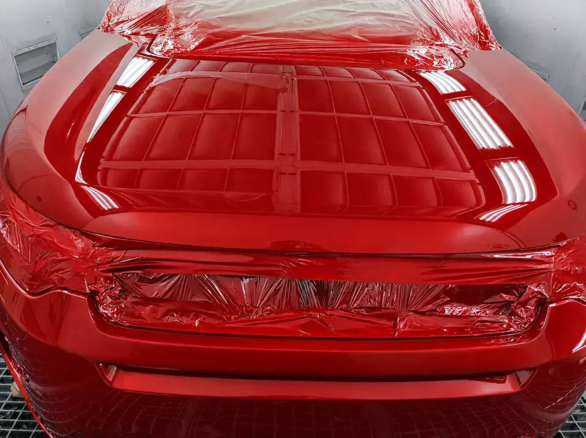 Coche deportivo rojo visto desde el frente, mostrando el capó y los faros brillantes.