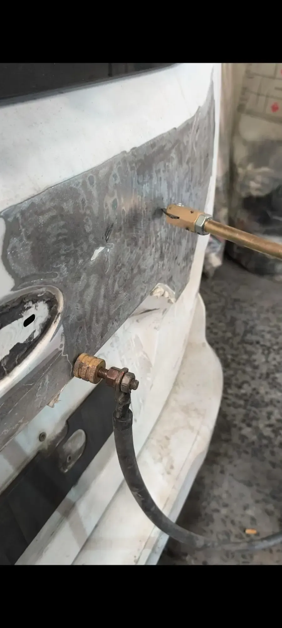 Primer plano de un parachoques de coche sujeto con cinta adhesiva o abrazaderas durante su reparación