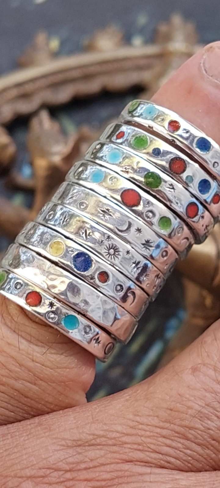 Primer plano de un dedo que lleva un anillo de plata adornado con piedras preciosas multicolores.