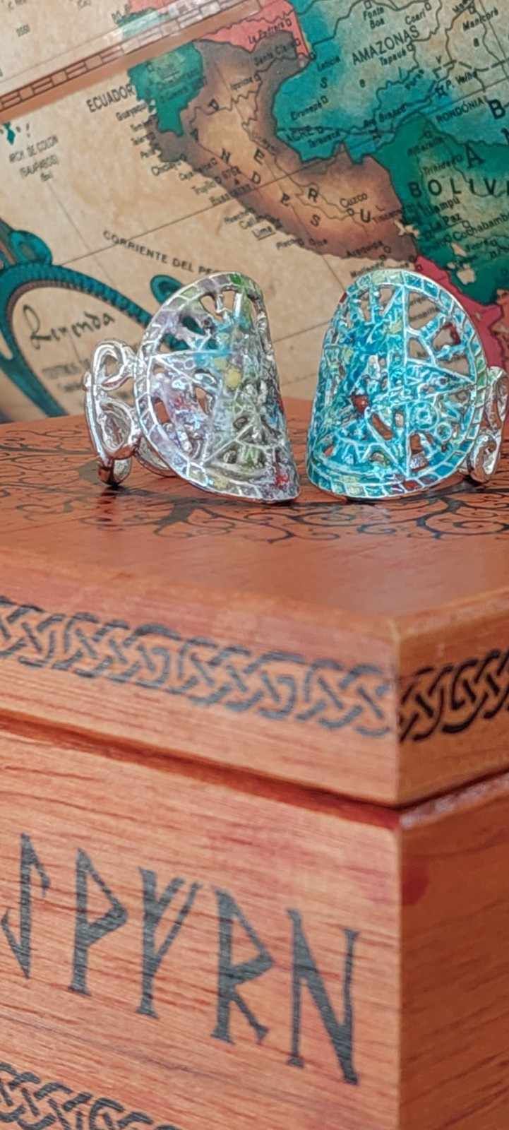 Dos adornos en forma de corazón con cuentas turquesas sobre un cofre de madera tallada.