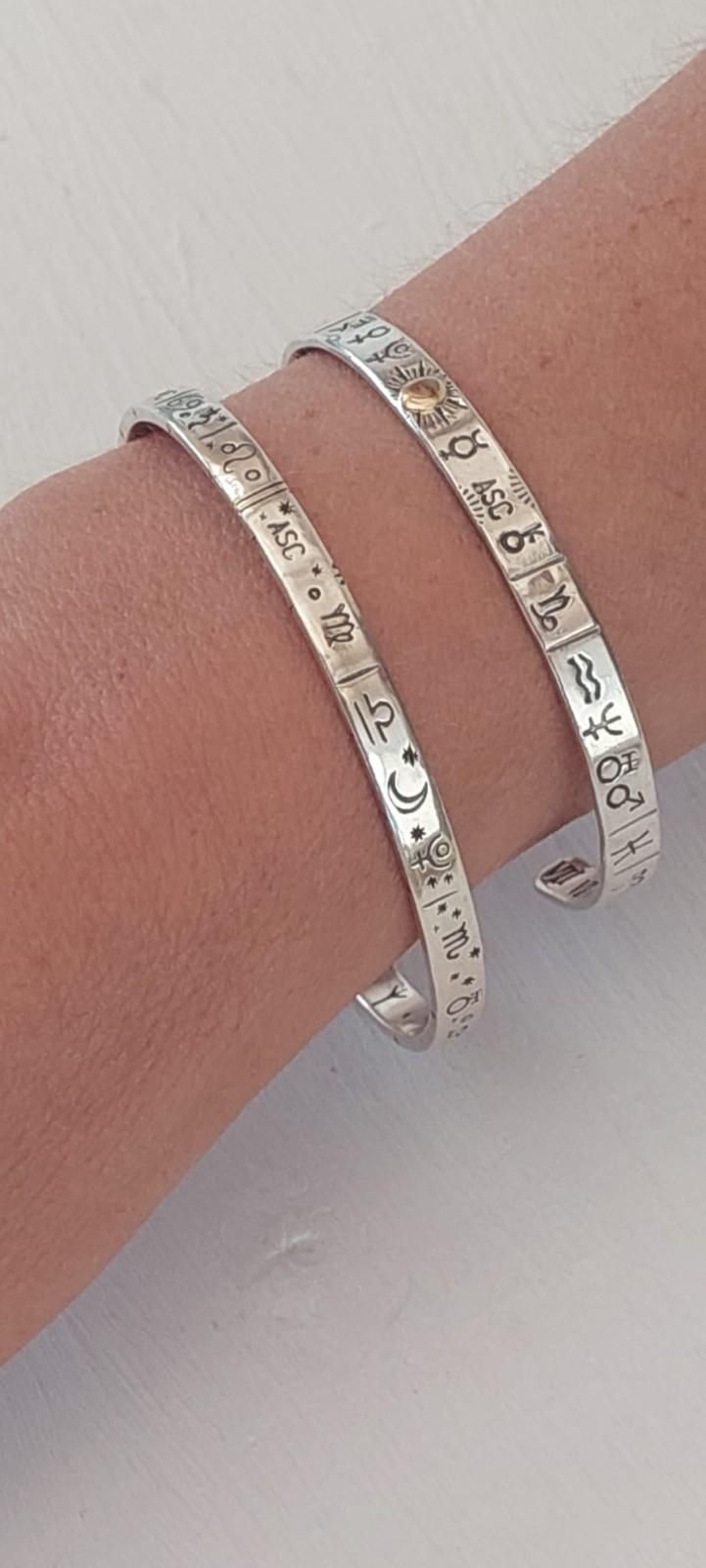 Dos pulseras de plata con símbolos grabados en una muñeca