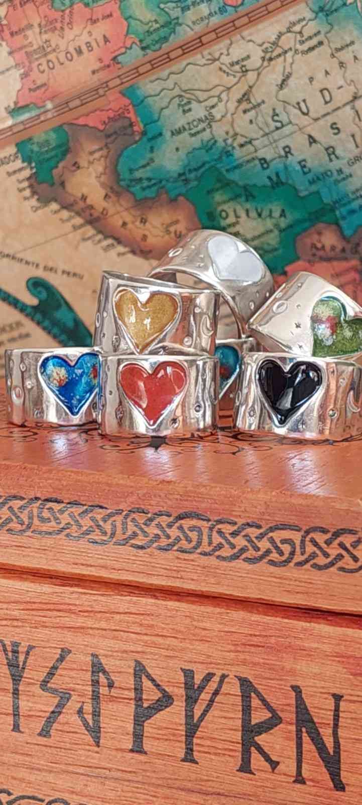 Cuatro pequeños vasos de chupito con estampado de corazones sobre una superficie de madera con un fondo de mapa antiguo.