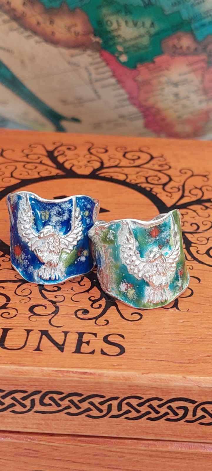 Dos tazas de cerámica azul y blanca sobre una superficie de madera tallada con un mapa al fondo.