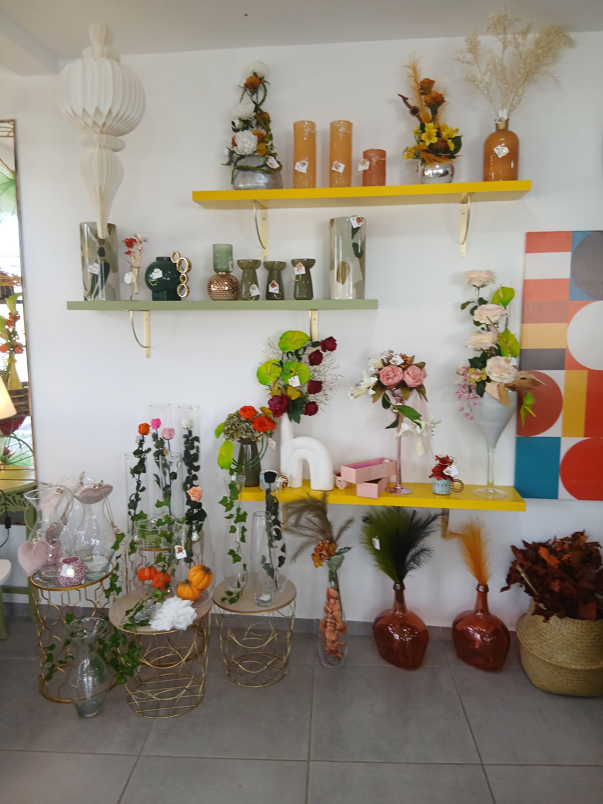 Une personne arrange des fleurs sur une table avec des ciseaux et de la verdure. Fleurs rose pâle et blanches, papier brun.