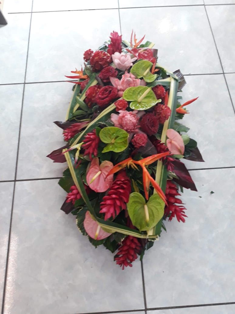 Composition florale de fleurs rouges, roses et vertes, sur un sol carrelé blanc.