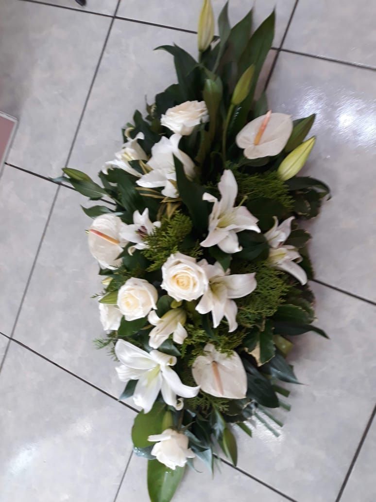 Composition florale blanche, lys et roses, sur un sol carrelé.