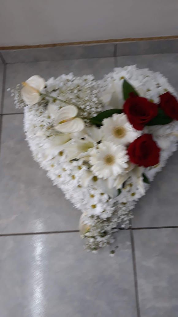 Composition florale en forme de cœur ; roses blanches et rouges, posée sur un sol carrelé.