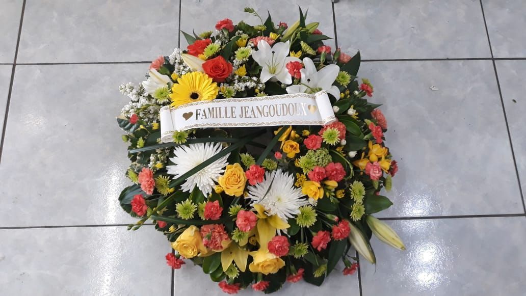 Couronne de fleurs avec bannière blanche, fleurs éclatantes, couleurs variées.