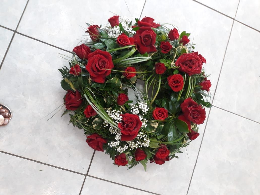 Couronne de roses rouges sur un sol carrelé.