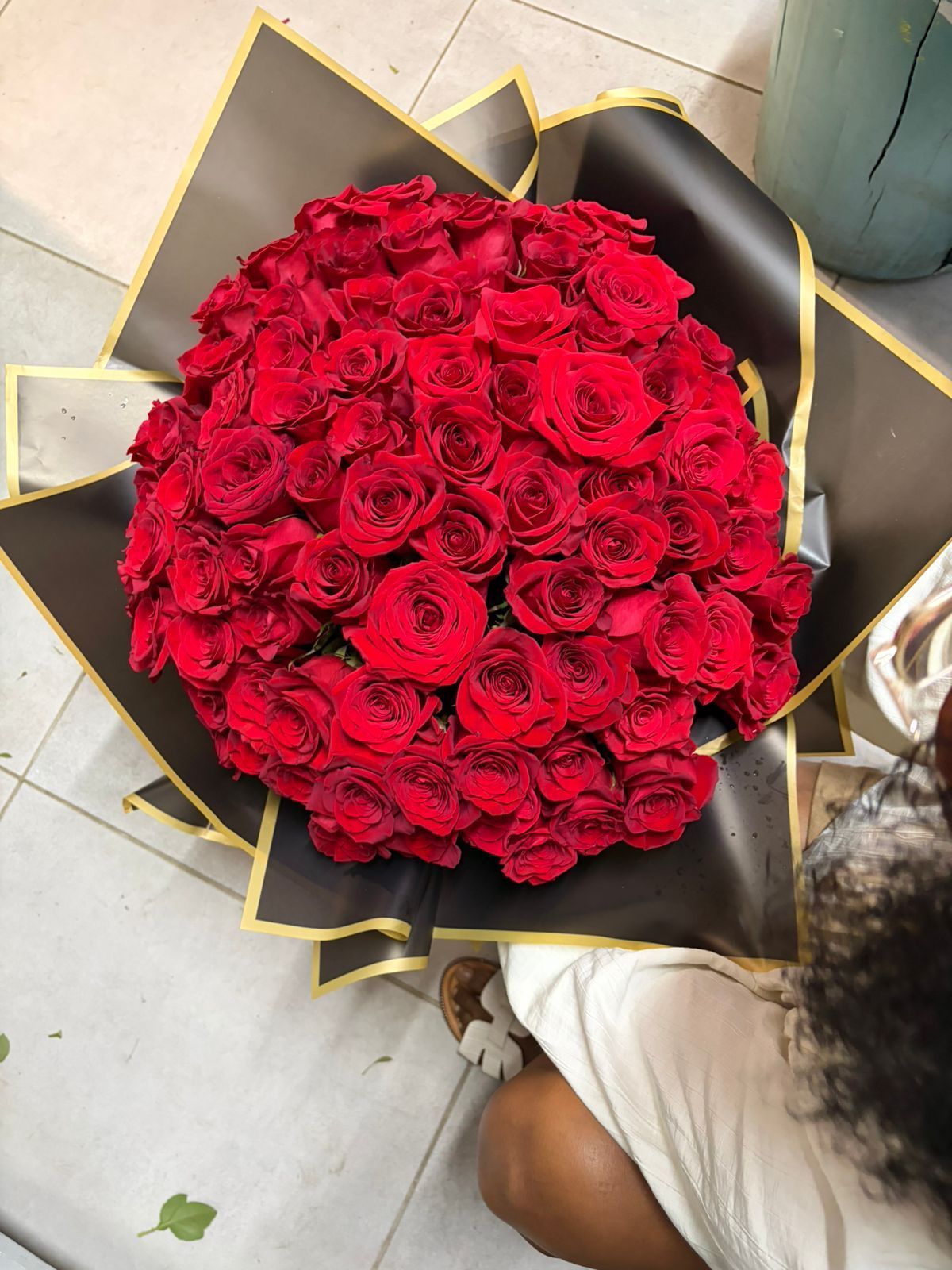 Bouquet de nombreuses roses rouges enveloppées dans du papier noir et or.