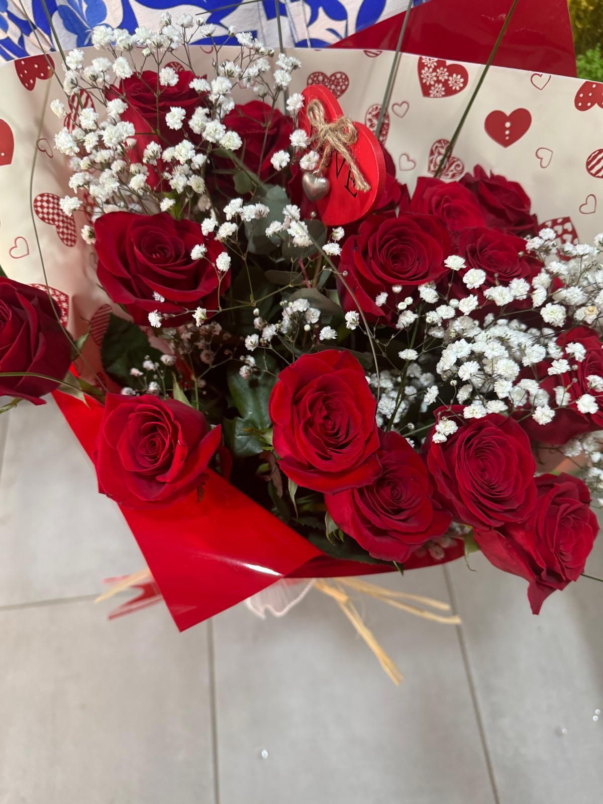 Couronne de roses rouges et de verdure, vue de dessus, sur une surface carrelée.