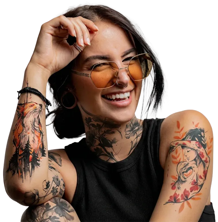 Eine lächelnde Person mit sichtbaren Arm- und Nackentätowierungen, die eine getönte Sonnenbrille trägt, posiert.