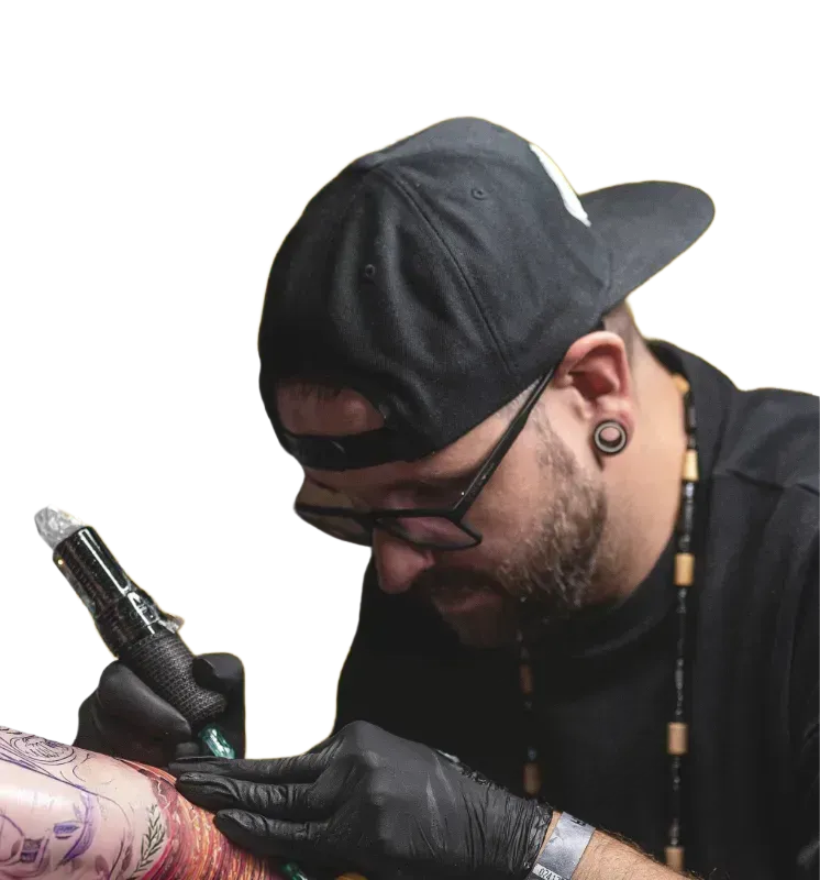 Eine Person benutzt eine Tätowiermaschine, um an einem Tattoo auf einem Arm zu arbeiten.