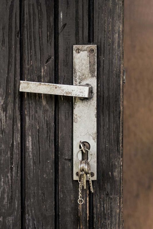 Un primer plano de una manija de puerta con llaves en una puerta de madera.