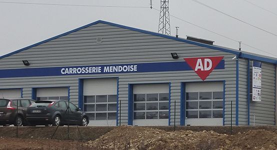 Carrosserie Mendoise, atelier de réparation automobile avec bâtiment gris, trois portes de garage et logo AD.