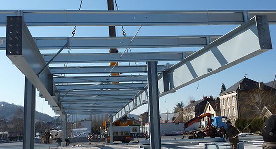 Des poutres d'acier sont soulevées par une grue lors de la construction d'un bâtiment.