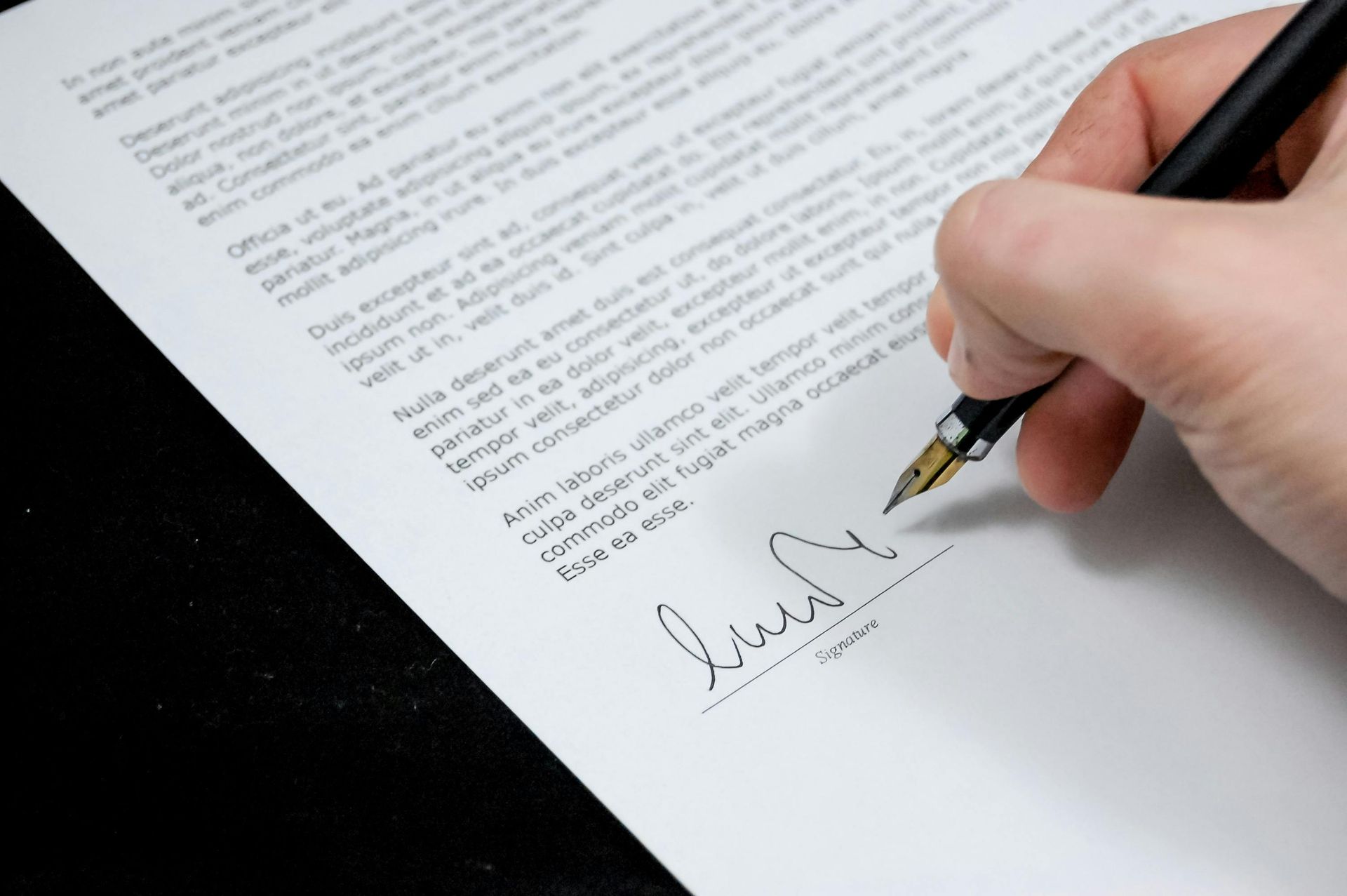 Firma a mano de un documento con bolígrafo sobre una página en blanco.