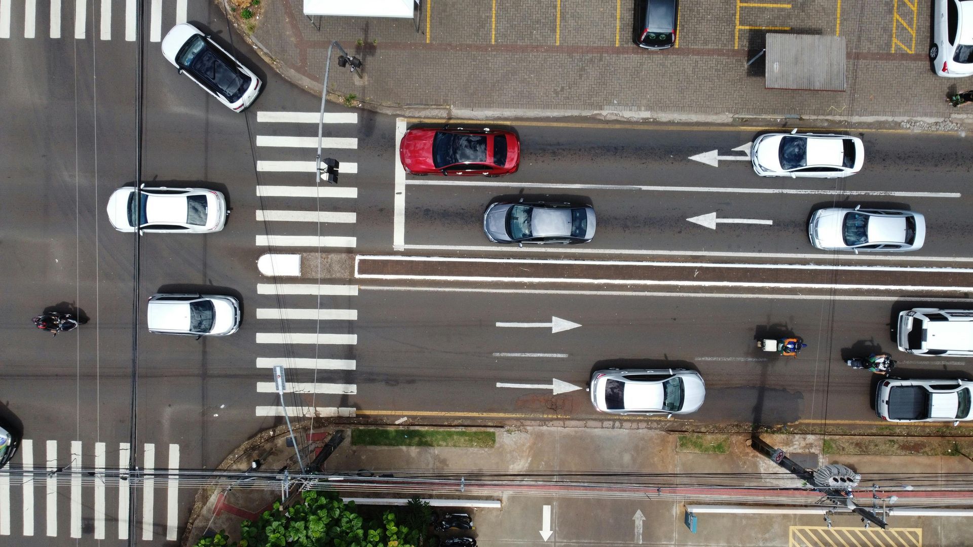 Vista aérea de una concurrida intersección urbana con coches, pasos de peatones, señalización vial y semáforos.
