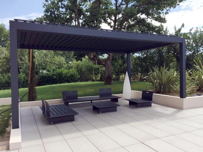 Terrasse carelée avec table et chaises sous une pergola.