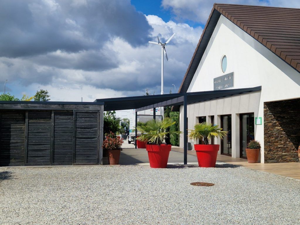 Deux arbustes dans des gros pots rouge devant une brasserie.