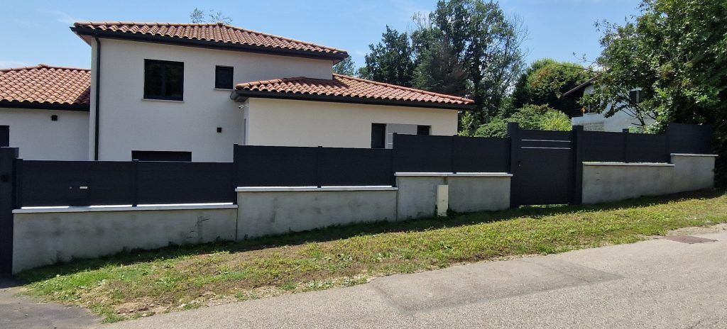 Un grand portail et clôture devant une grande habitation 2.