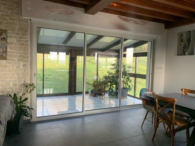 Une baie vitrée coulissante fermé d'un salon donnant sur une véranda.