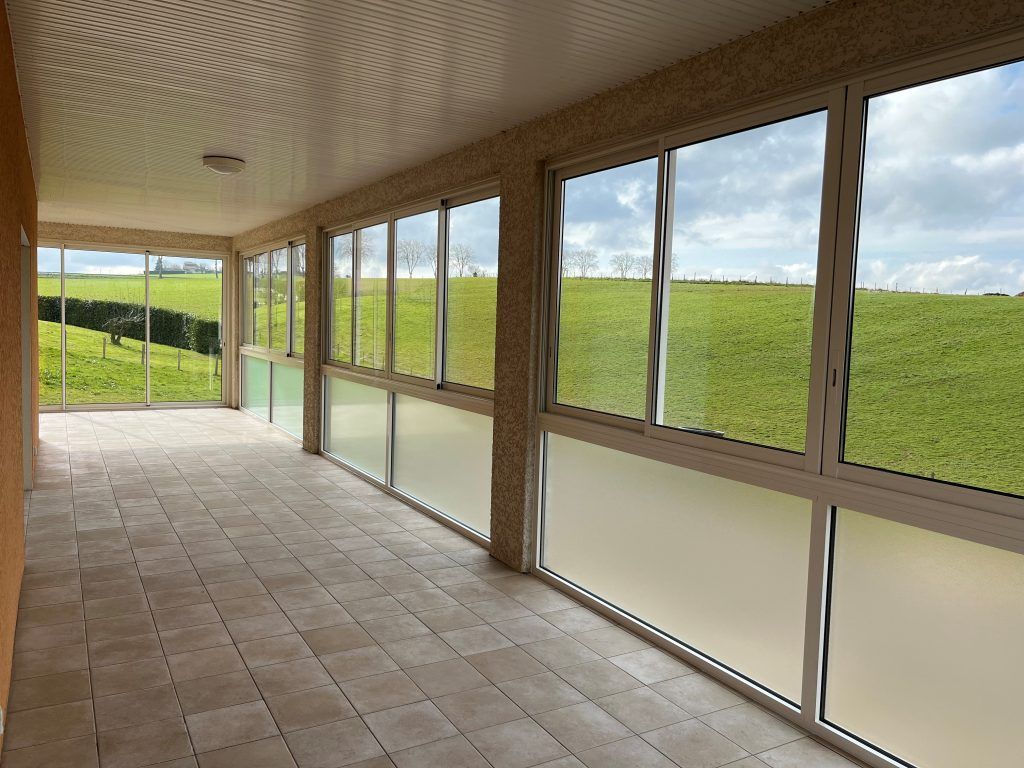 Plusieurs fenêtres et baies vitrées d'une pièce en longueur.