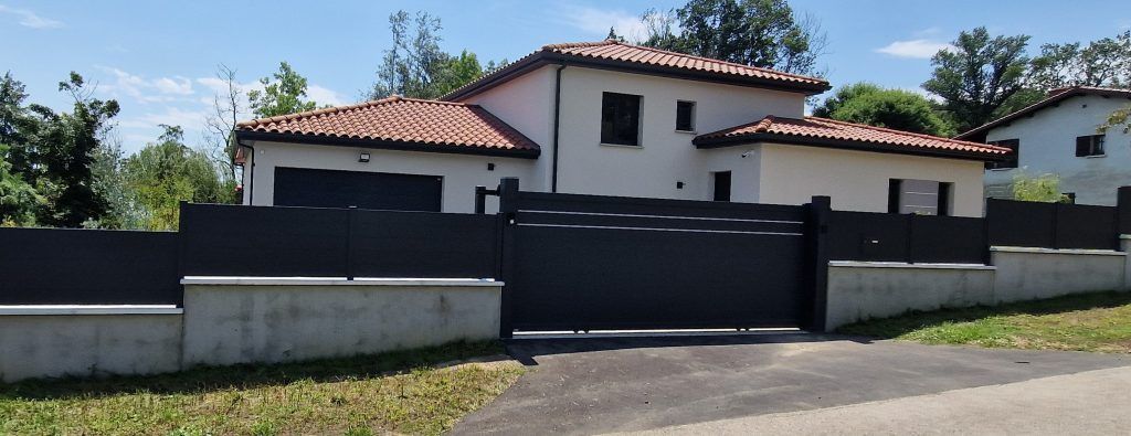 Un grand portail et clôture devant une grande habitation 1.