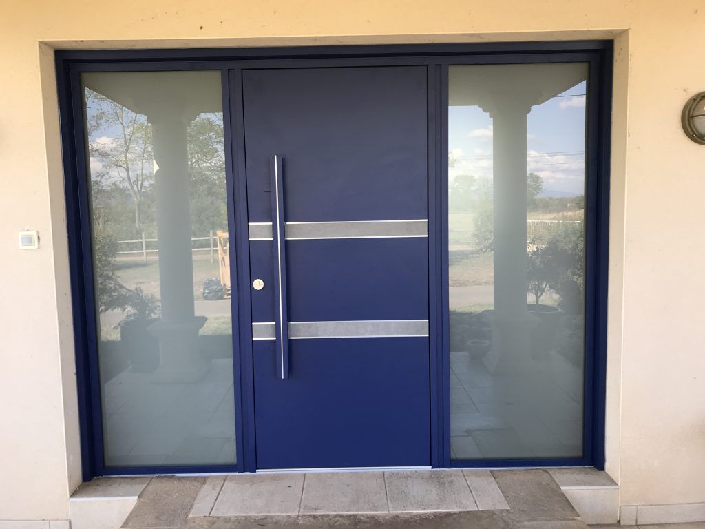 Une porte bleu en aluminium entre deux grande vitres fumées.