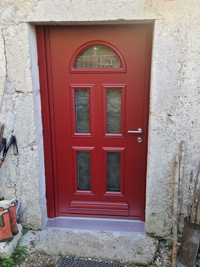 Une porte rouge avec quatre petites fenêtres.