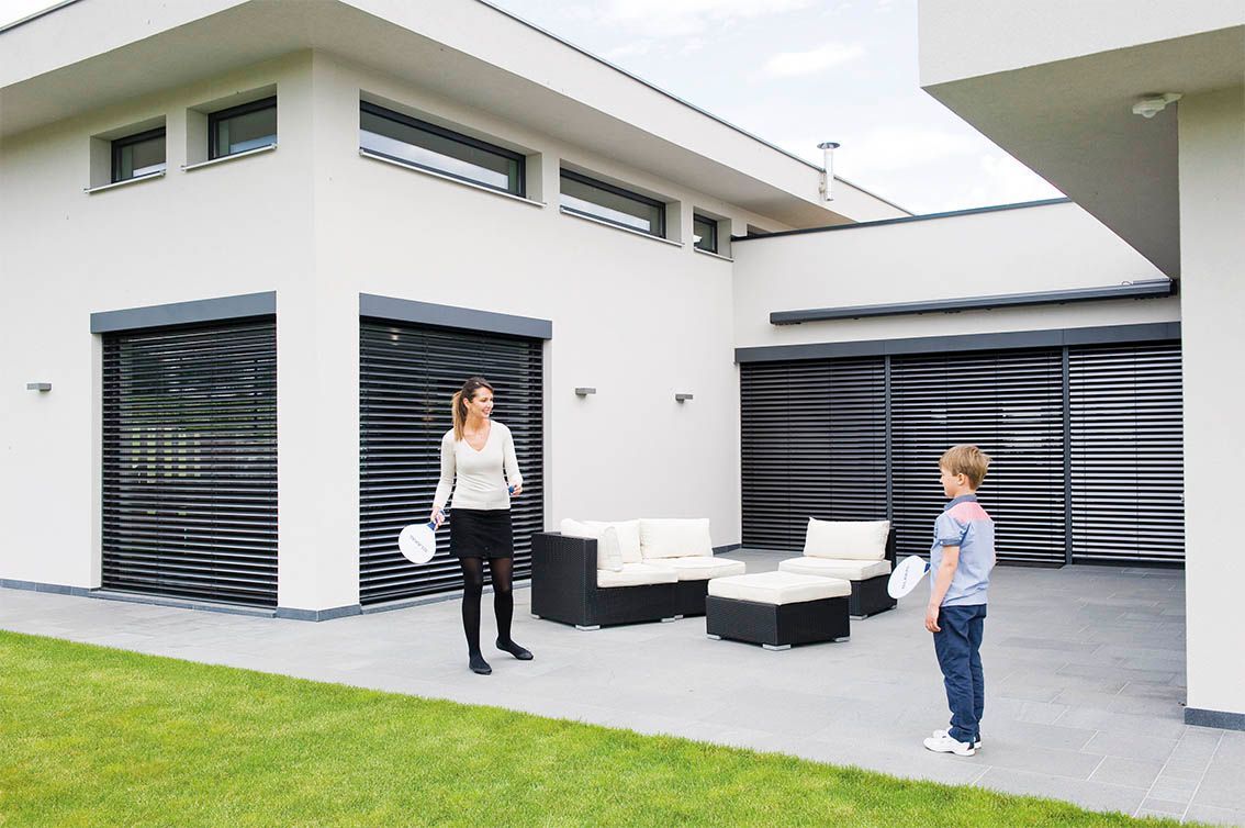 Une femme et un enfant sur la terasse d'une maison.