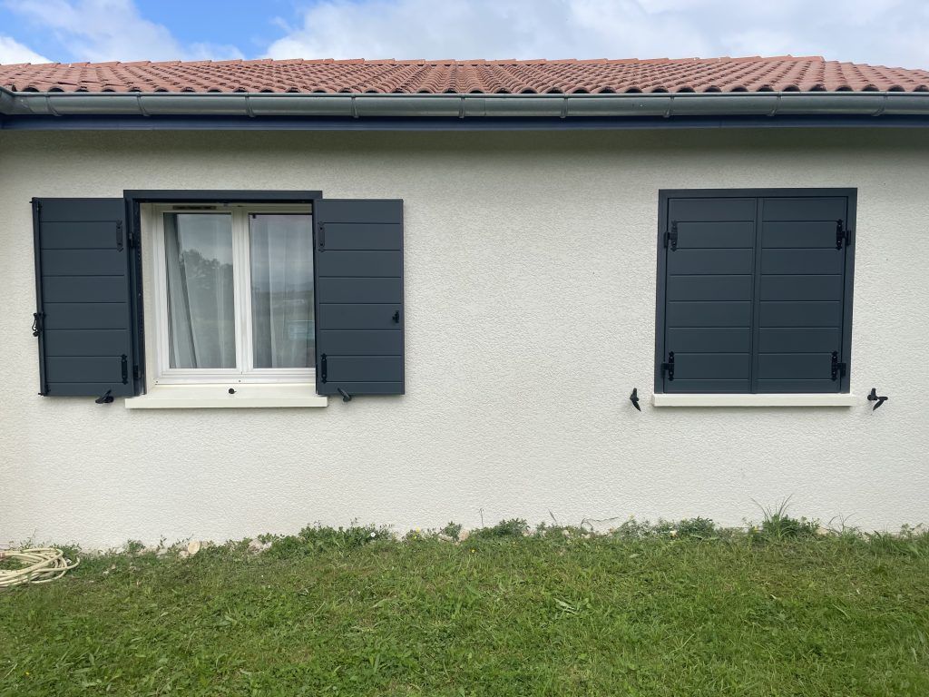 Maison avec des volets battants dont l'une des fenêtres est fermée.