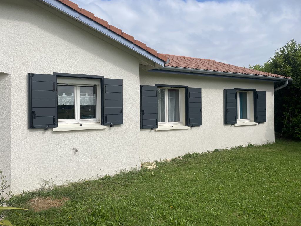 Maison avec des volets battants noir ouvert.