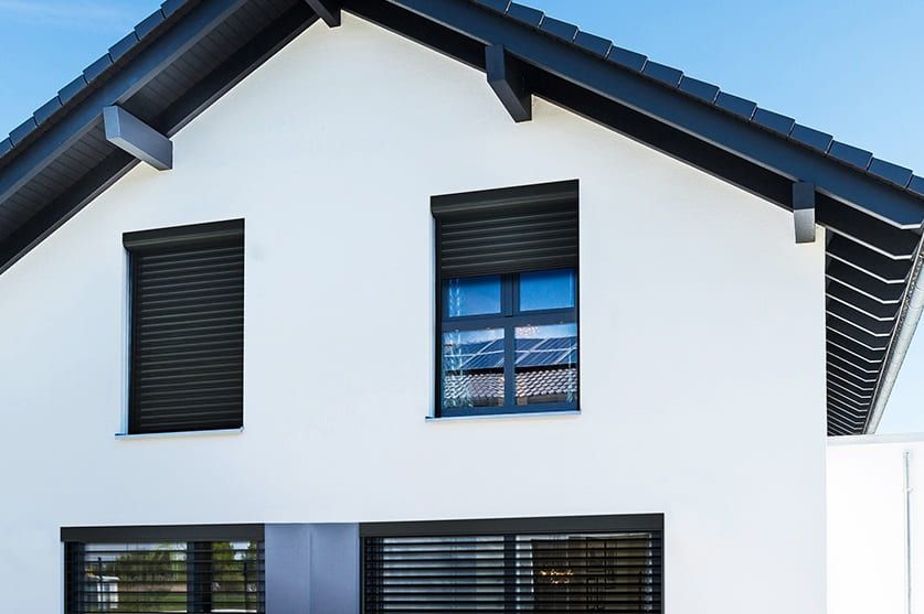 Fenêtres et volets de couleur noir d'une maison blanche.