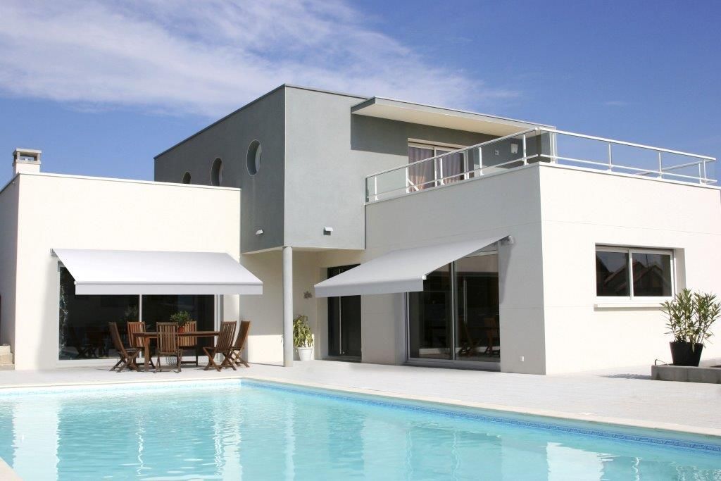 Une grande maison en plusieurs bloc devant une piscine.