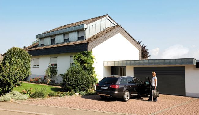 Un personne devant un véhicule devant un garage fermé.