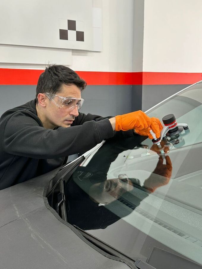 Parabrisas de automóvil agrietado con tres puntos de impacto y grietas irradiadas.