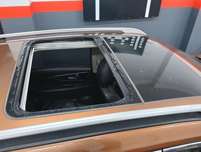 Fotografía del interior del automóvil con el techo corredizo abierto, que muestra un cielo azul brillante y tapicería beige.