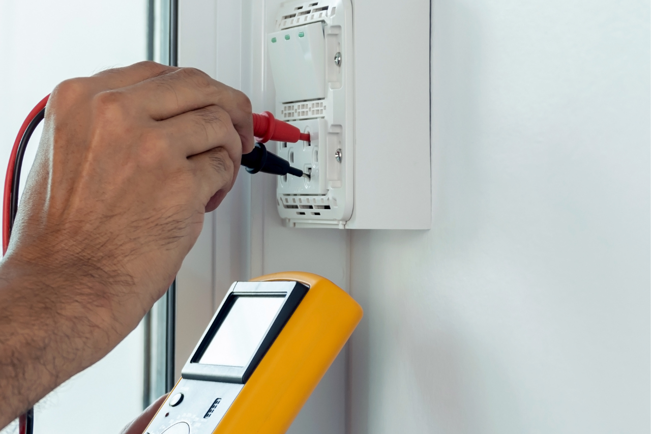 Une personne utilise un multimètre pour tester un interrupteur d'éclairage.