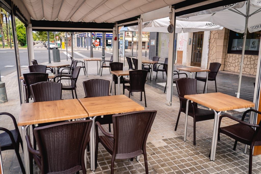 Restaurante al aire libre con mesas y sillas bajo un patio cubierto.