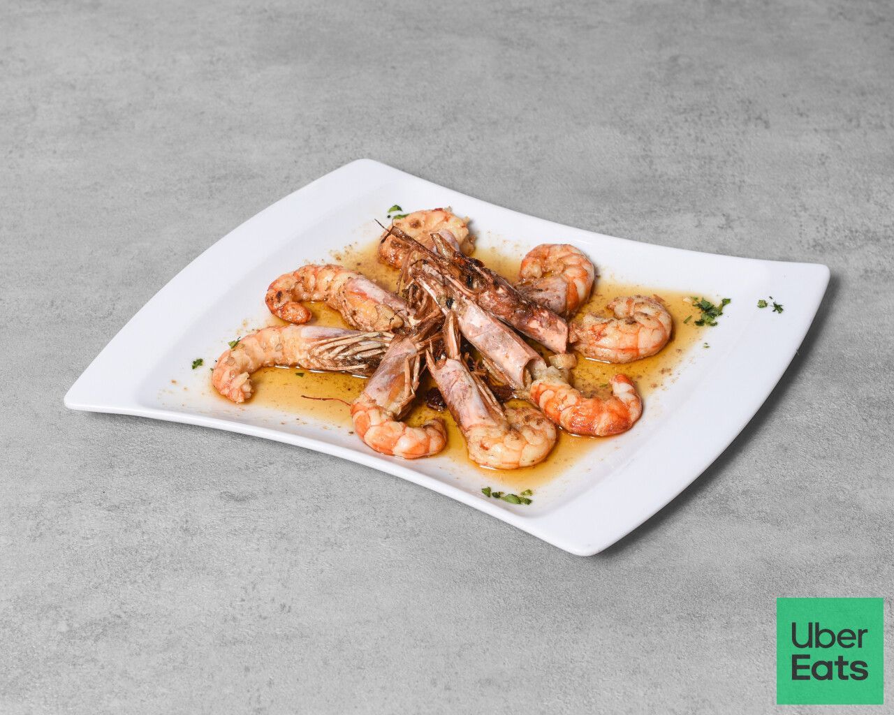 Plato de camarones cocidos con salsa, logo de Uber Eats en esquina.