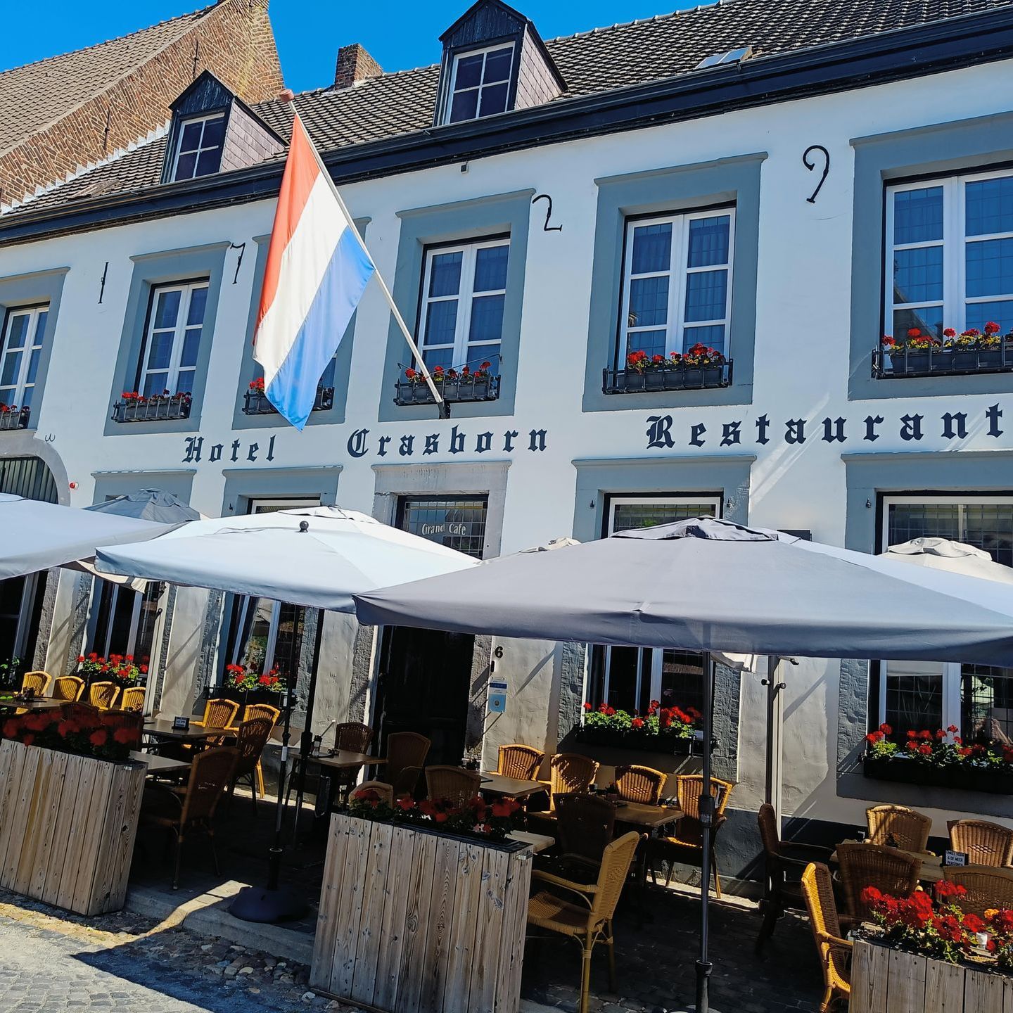 Een restaurant met tafels en parasols ervoor