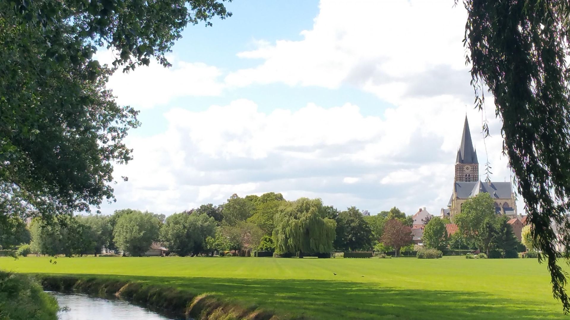 Een rivier stroomt door een grasveld met een kerk op de achtergrond